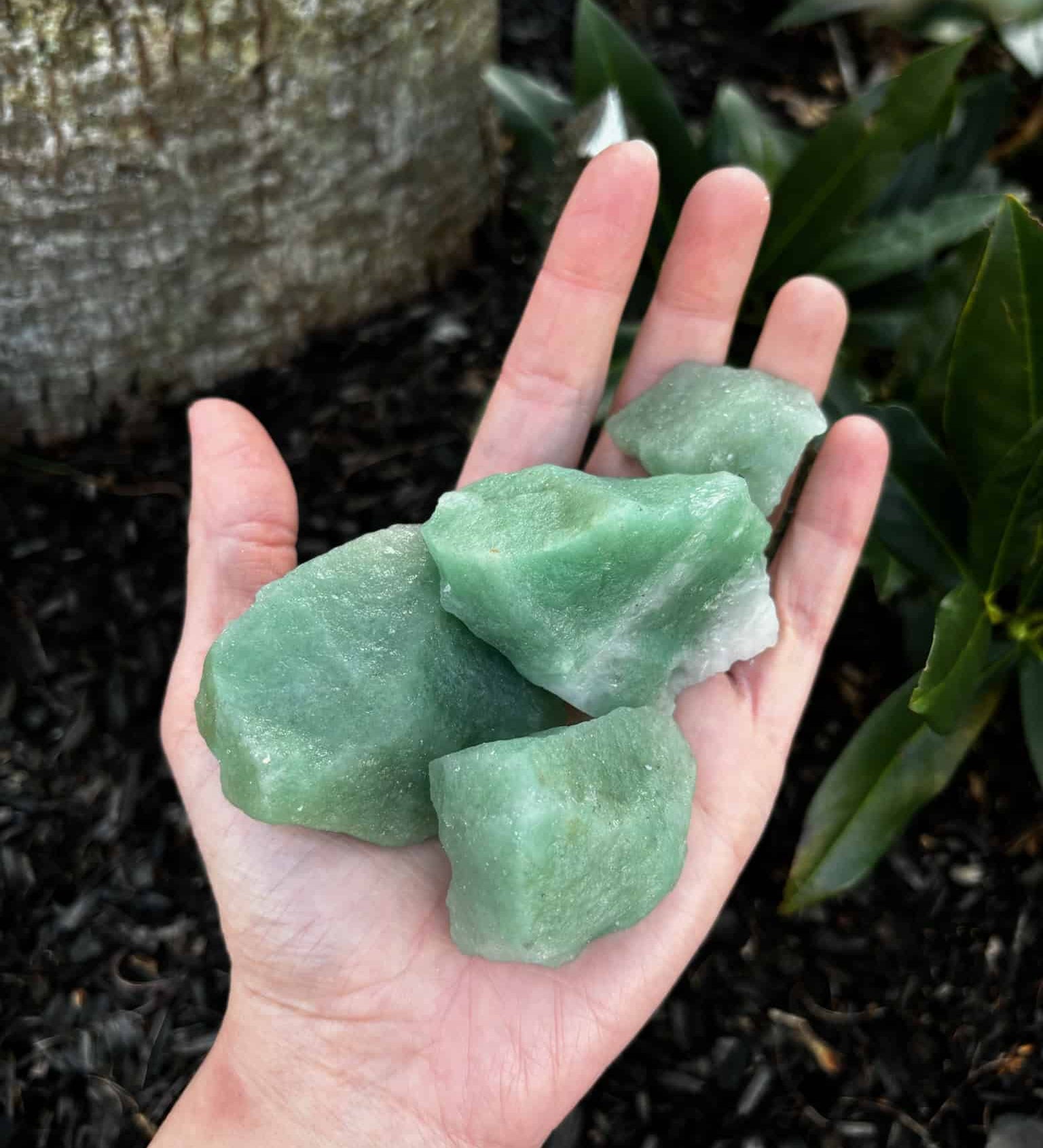 Rough Green Aventurine in palm of hand over ground