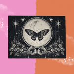The Black & White Moon Butterfly Small Tapestry on a pink and orange background.