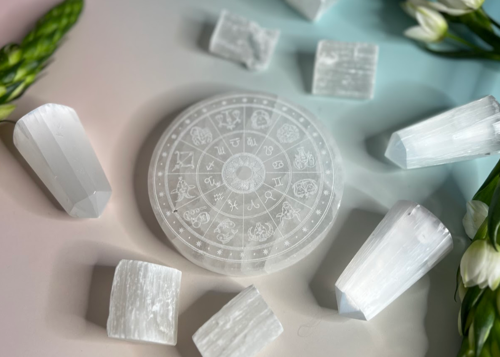 Selenite crystal grid with selenite blocks on a light blue background with greenery.