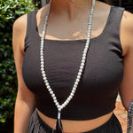 model wearing a black tank top in front of greenery with a howlite mala around her neck