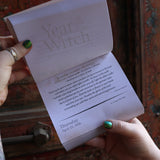 Someone holding the Year of the Witch 2026 Day-to-Day Calendar up in front of a door, showing off the pages.