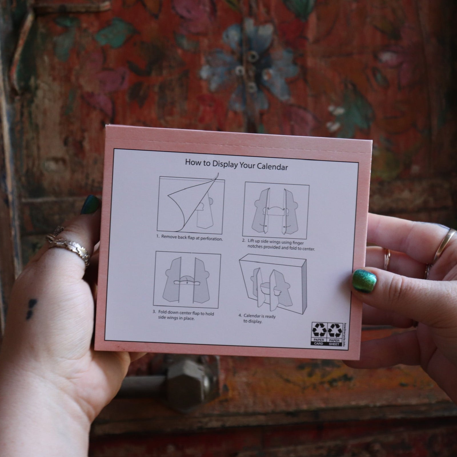 Someone holding the Year of the Witch 2026 Day-to-Day Calendar up in front of a door, showing off the back.