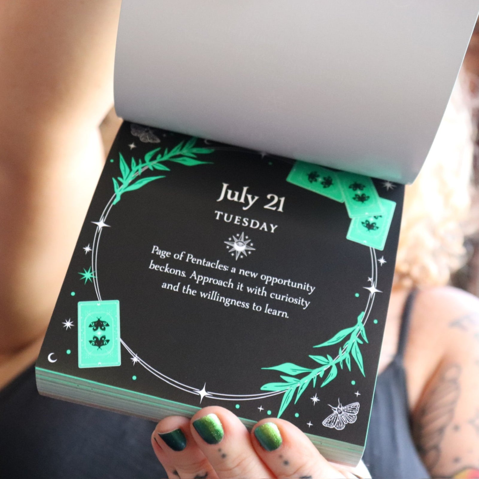 Someone holding the 2026 Witch's Calendar Daily Magick Day-to-Day Calendar, showing off the pages, showing off the pages.