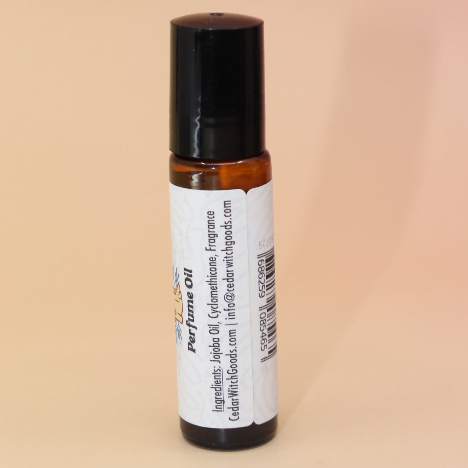 The Ritual 10ml Roll-On Perfume Oil on a pink and yellow background, showing off the back.