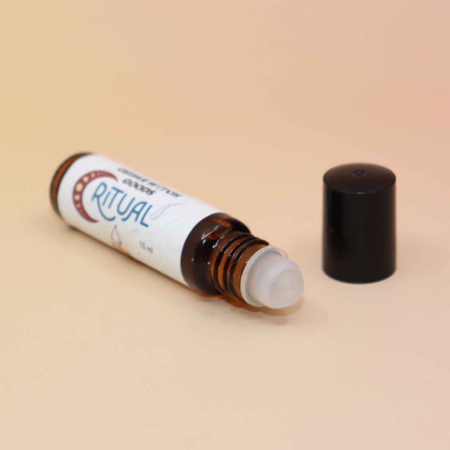 The Ritual 10ml Roll-On Perfume Oil on a pink and yellow background.