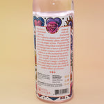 An up-close image of the back of the Love Spell Spiritual Cleansing Water 7.5 oz. on a pink and yellow background.