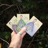 Someone holding all three of the 6 Pan Vegan Eyeshadow Palettes from Lauren Good Day in front of a green bush.