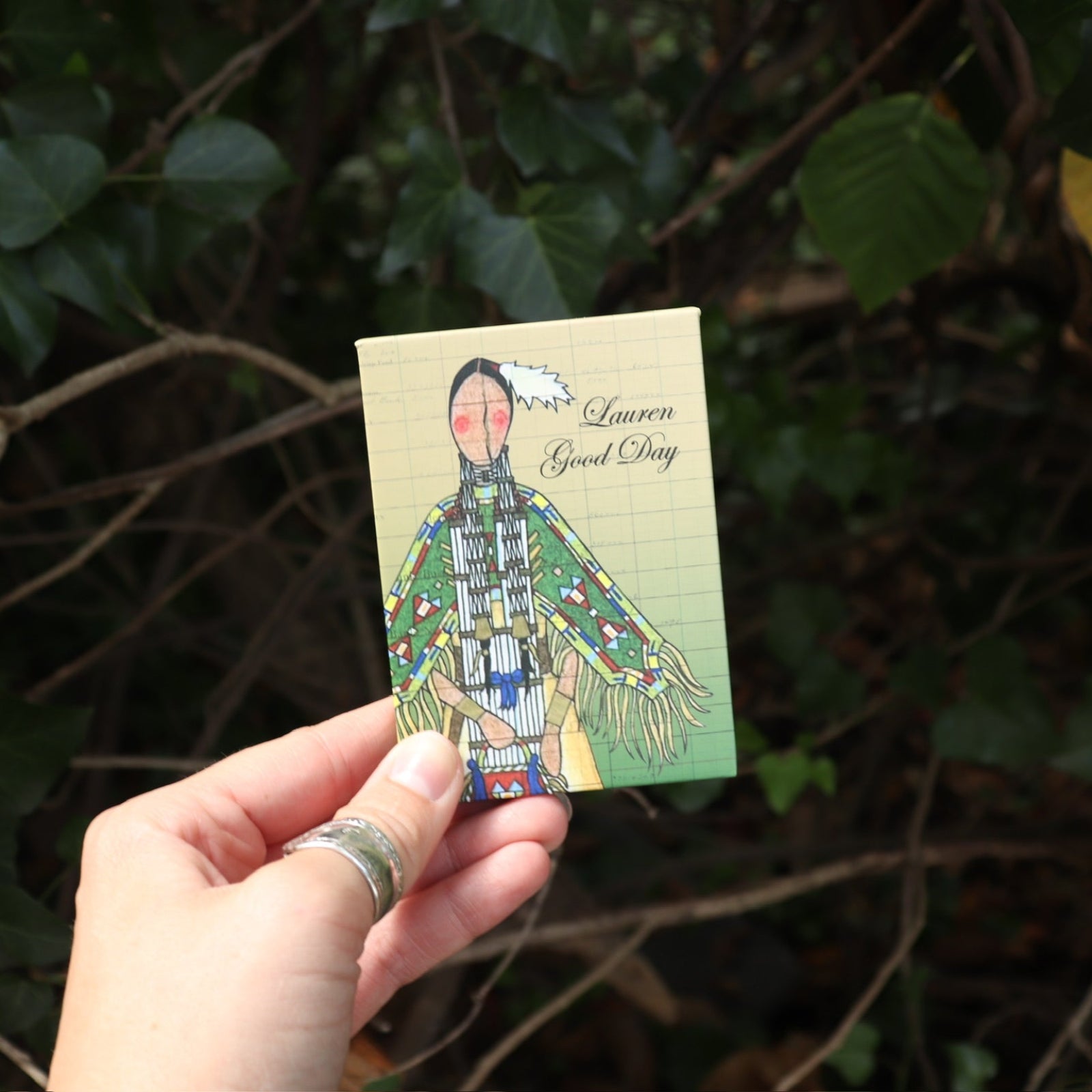 Someone holding the Plant Medicine 6 Pan Vegan Eyeshadow Palette in front of a green bush.