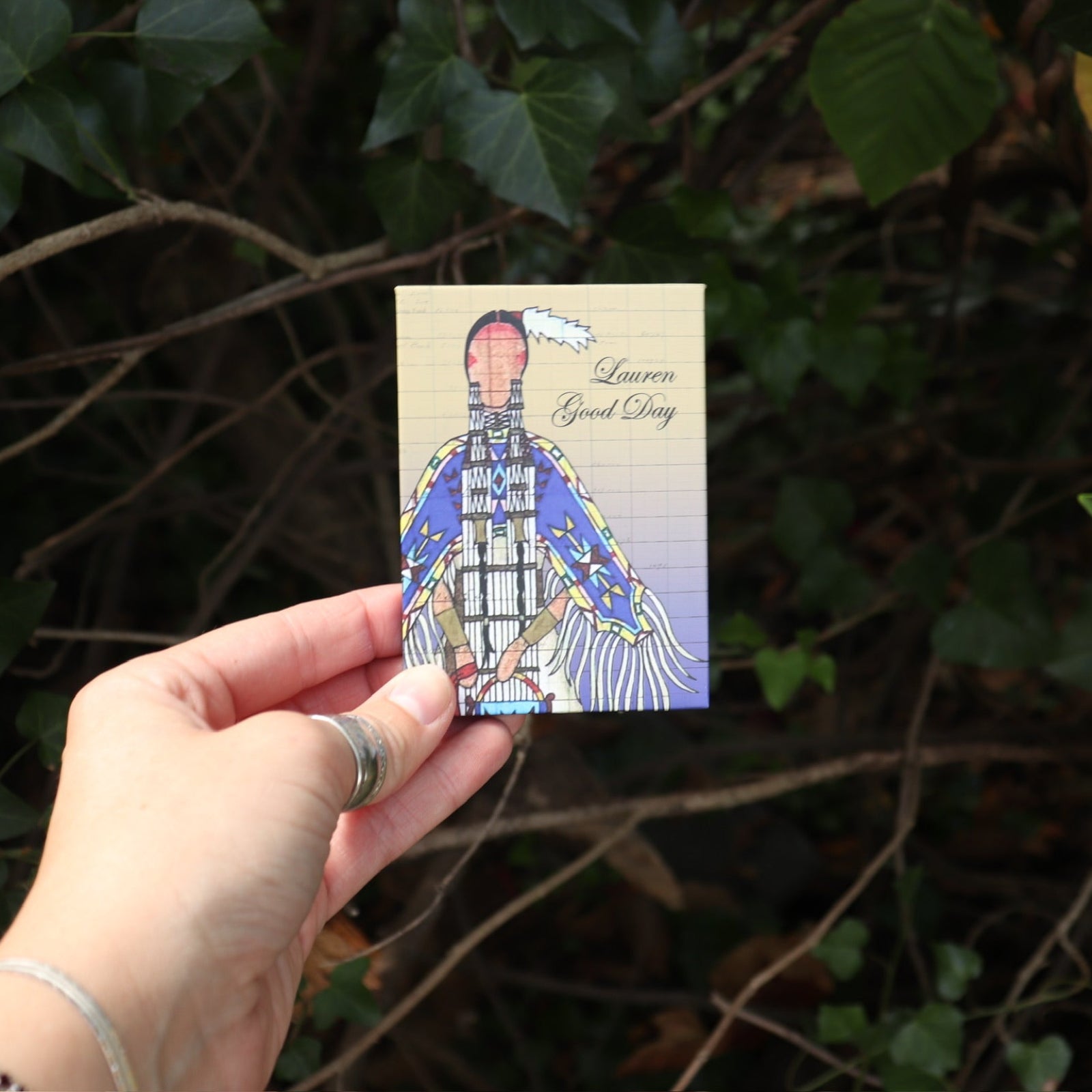 Someone holding the Healing Waters 6 Pan Vegan Eyeshadow Palette in front of a bush.
