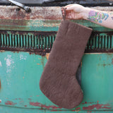 Someone holding the Handmade Gray Mushroom Felt Boho Stocking in front of a vintage teal Volkswagen bus, showing off the back.