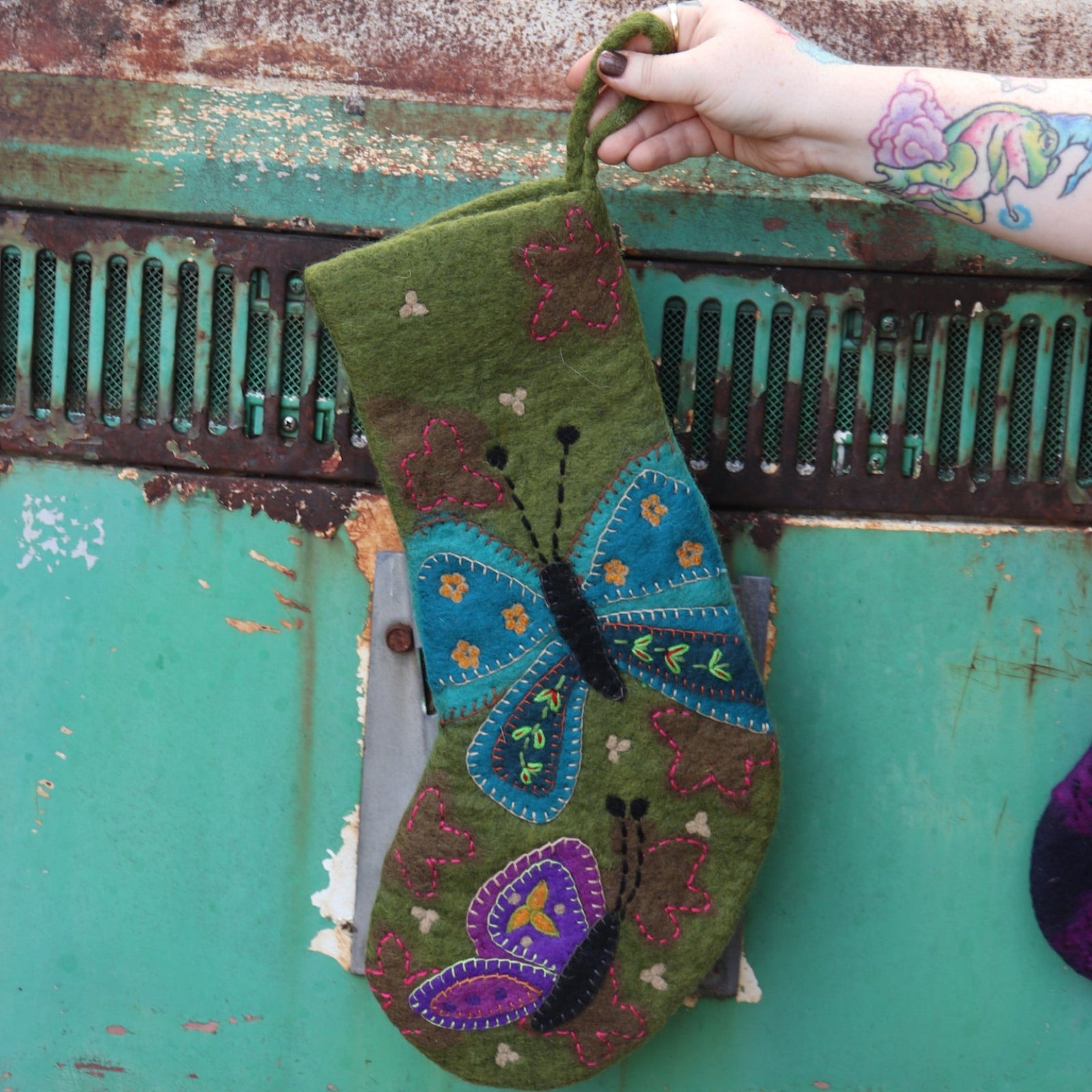 Someone holding the butterfly Folk Art Embroidered Pure Wool Felt Handcrafted Stocking in front of a vintage teal Volkswagen bus.