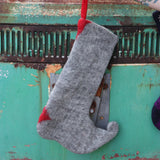 Someone holding the Handmade Red Mushroom Wool Felt Boho Stocking in front of a vintage teal Volkswagen bus, showing off the back.