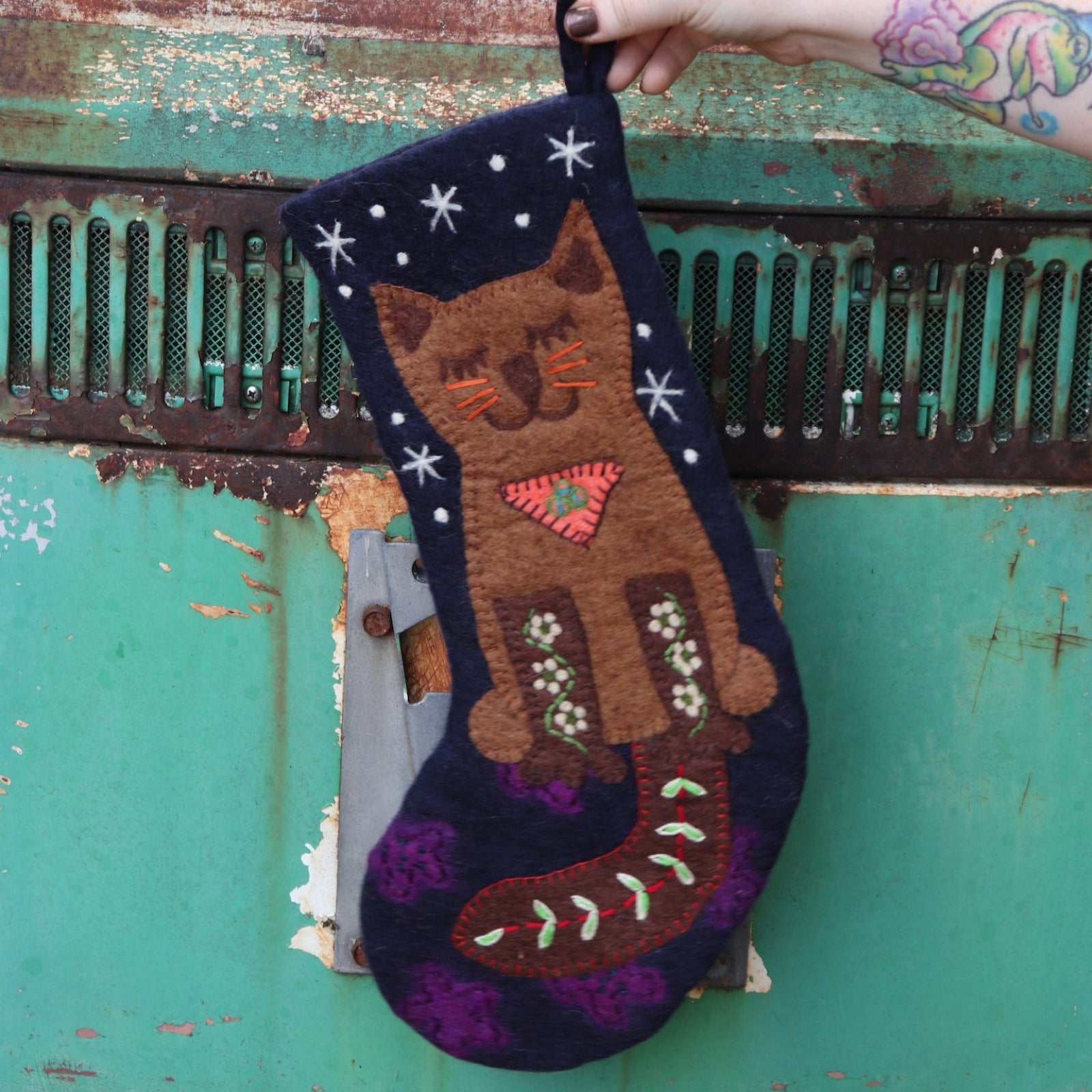 Someone holding the cat Folk Art Embroidered Pure Wool Felt Handcrafted Stocking in front of a vintage teal Volkswagen bus.