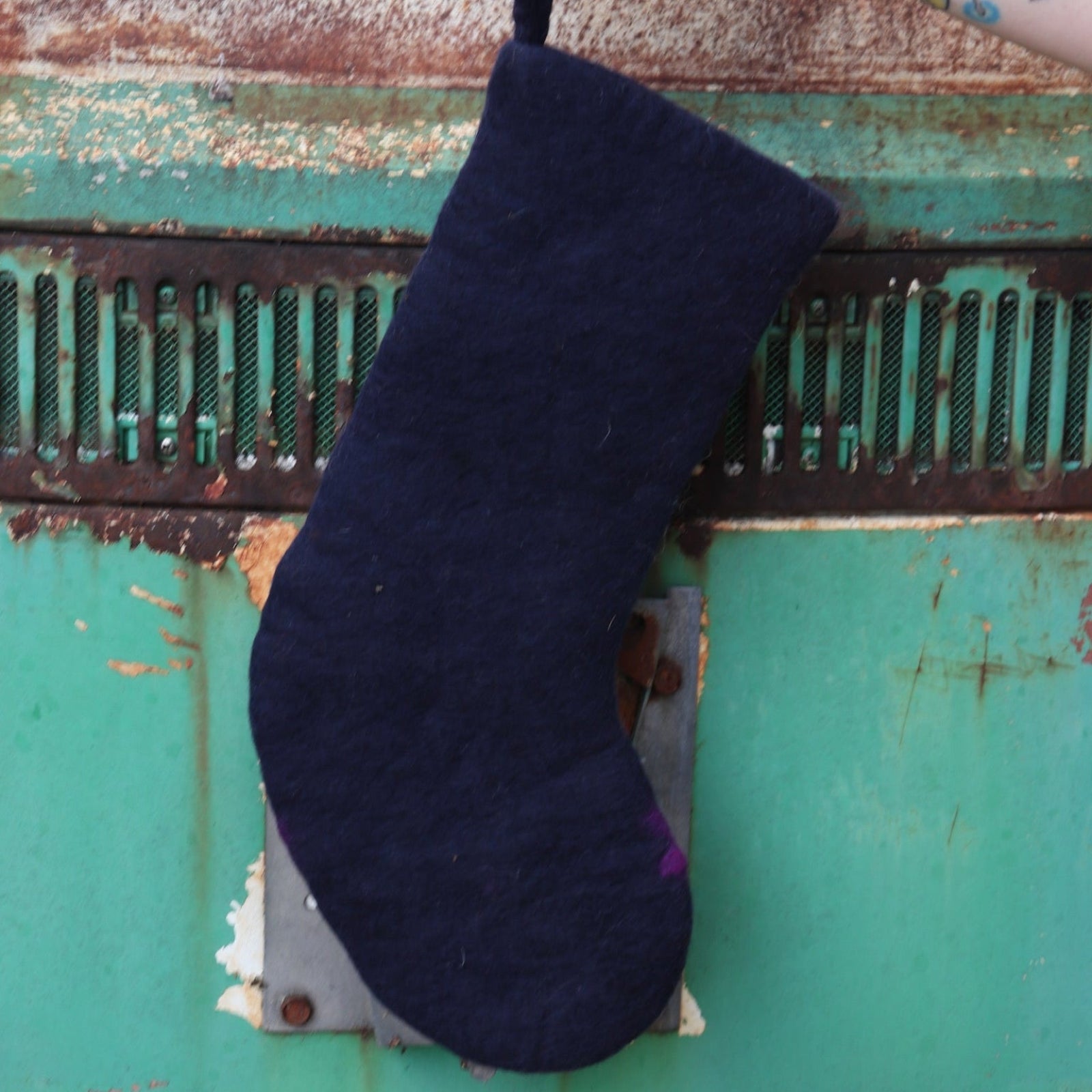 Someone holding the cat Folk Art Embroidered Pure Wool Felt Handcrafted Stocking in front of a vintage teal Volkswagen bus, showing off the back.