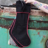 Someone holding the Set of 2 Black Floral Embroidered Stockings in front of a vintage teal Volkswagen bus, showing off the back.