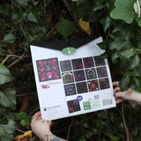 Someone holding the You Have the Magic 2026 Wall Calendar in front of a green bush, showing off the back.
