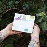 Someone holding the Effin' Birds 2026 Day-to-Day Calendar in front of a green bush, showing off the back.