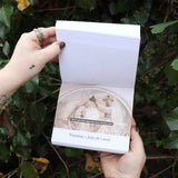 Someone holding the Punk History 2026 Day-to-Day Calendar open in front of a green bush, showing off the pages.