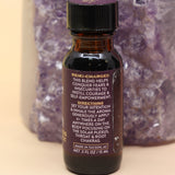 The Fearlesssness & Confidence Reiki Charged Anointing Oil in front of an amethyst tower all on a pink and yellow background.