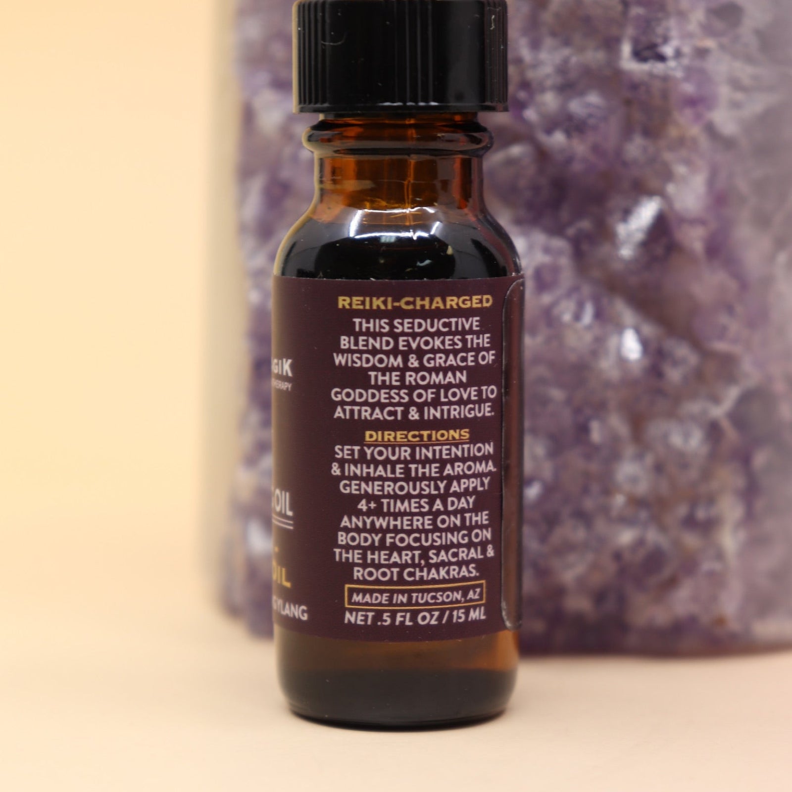 The Venus - A Love Oil Reiki Charged Anointing Oil in front of an amethyst tower all on a pink and yellow background.