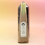 The straight Chartreuse Beeswax Taper Candles against a crystal tower all on a pink and yellow background.