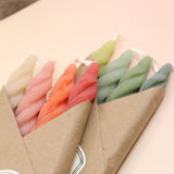 An up-close image of the Cave Glow Studio Beeswax Spiral Taper Candles on a pink and yellow background.