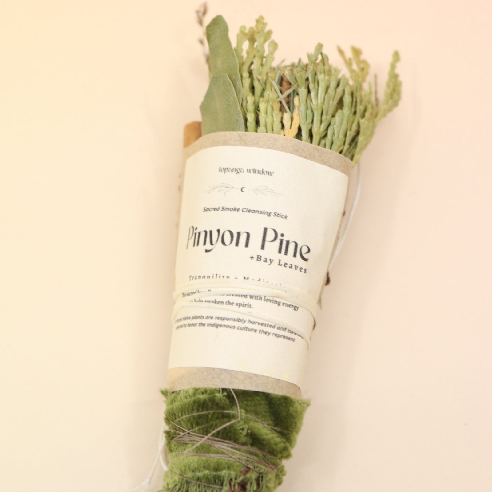 The Piñon Pine Sacred Smoke Cleansing Stick with Quartz Crystal on a pink and yellow background.