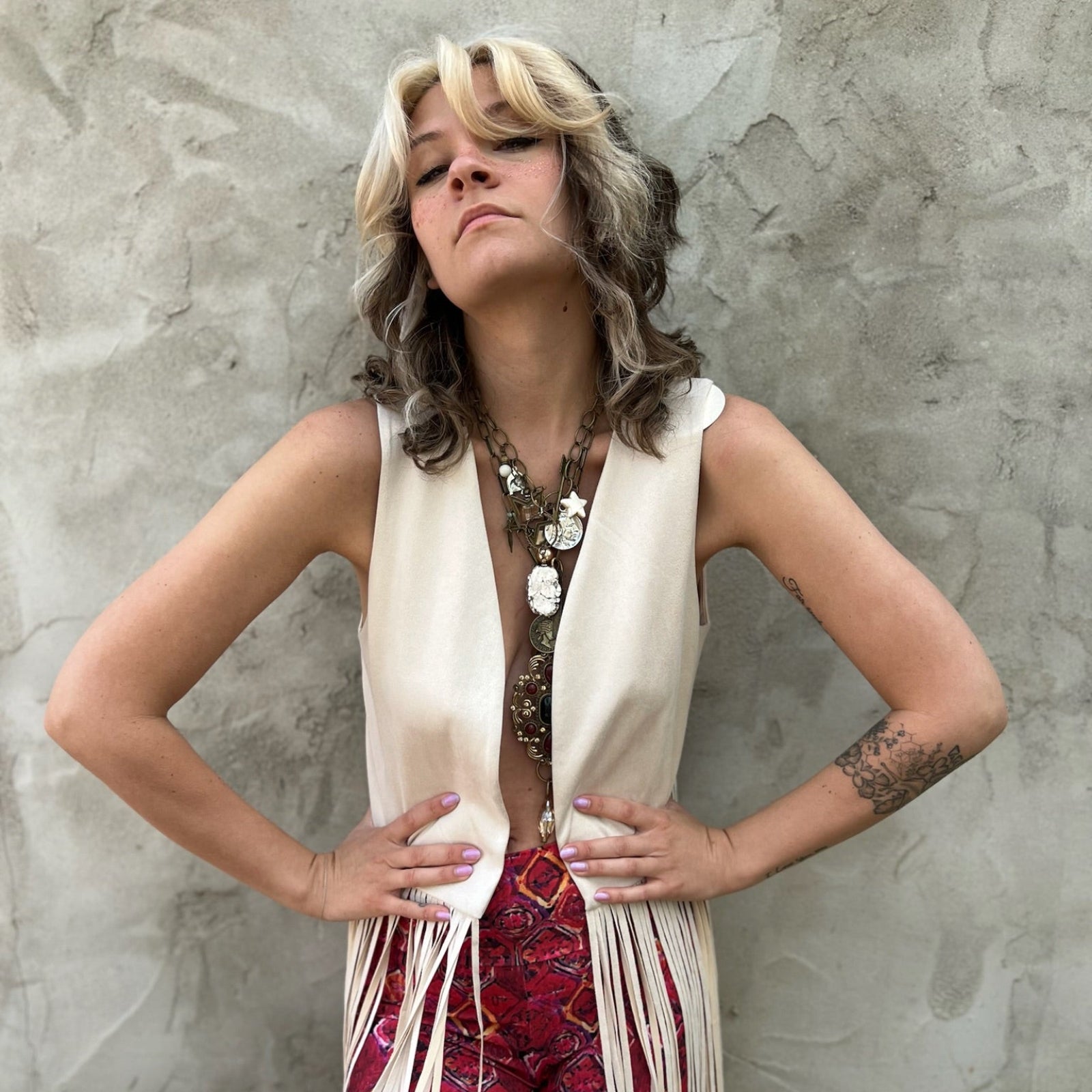 A woman wearing the cream Faux Suede Long Fringe Open Front Western Vest.