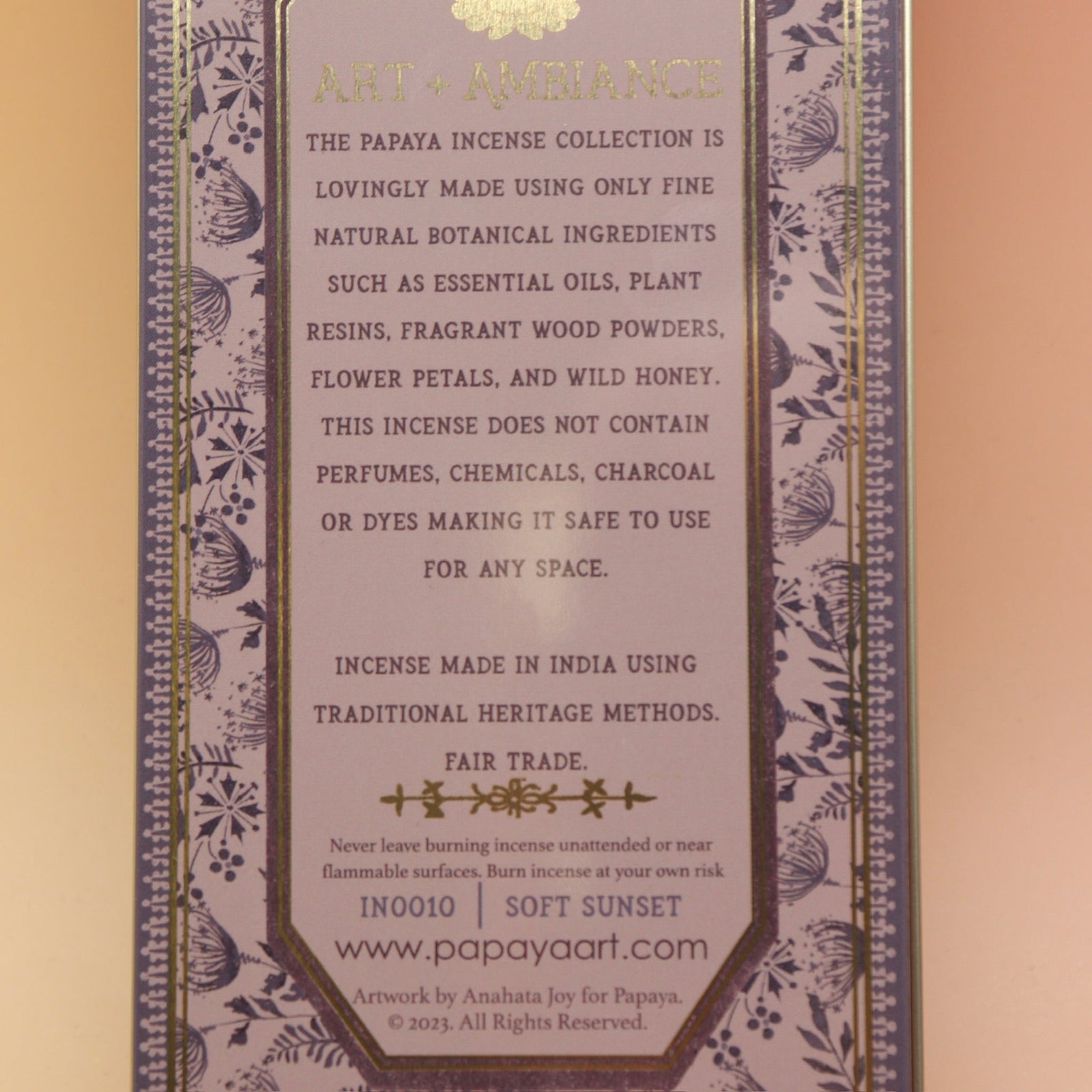The Soft Sunset Premium Incense on a pink and yellow background, showing off the back.