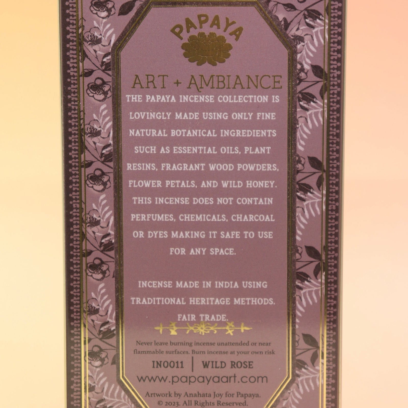 The Wild Rose Premium Incense on a pink and yellow background, showing off the back.