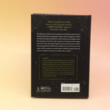 The Dictionary of Obscure Sorrows Hardcover Book in front of a pink and yellow background, showing off the back.