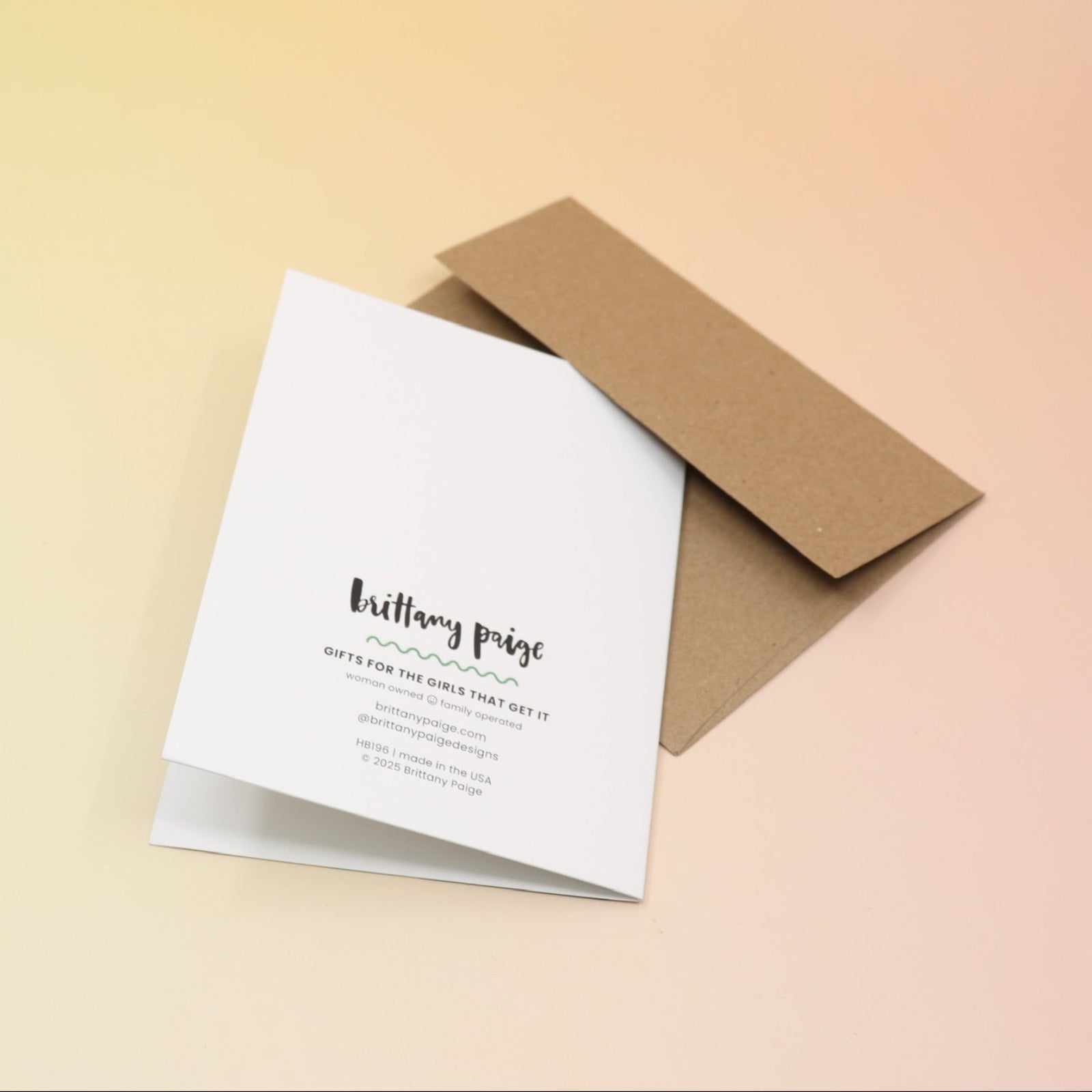 The Have A Wicked Birthday Card and its envelope on a pink and yellow background, showing off the back of the card.