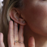 An up-close image of someone wearing the silver Memento Mori Mini Skull Stud Earrings.