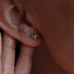 An up-close image of someone wearing the silver Memento Mori Mini Skull Stud Earrings.