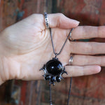 Someone holding the Priestess Obsidian Brass Necklace.