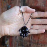 Someone holding the Priestess Obsidian Brass Necklace.