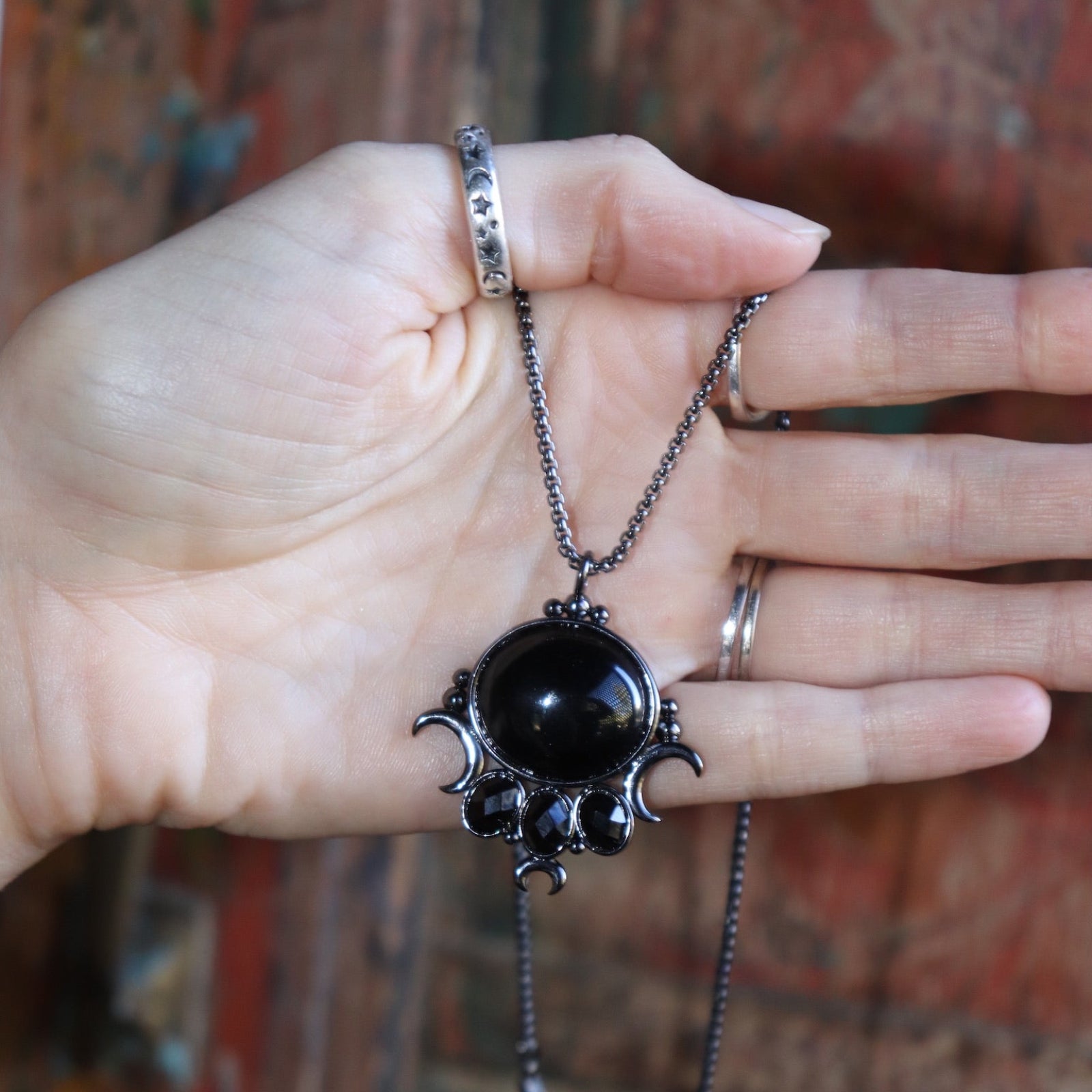 Someone holding the Priestess Obsidian Brass Necklace.