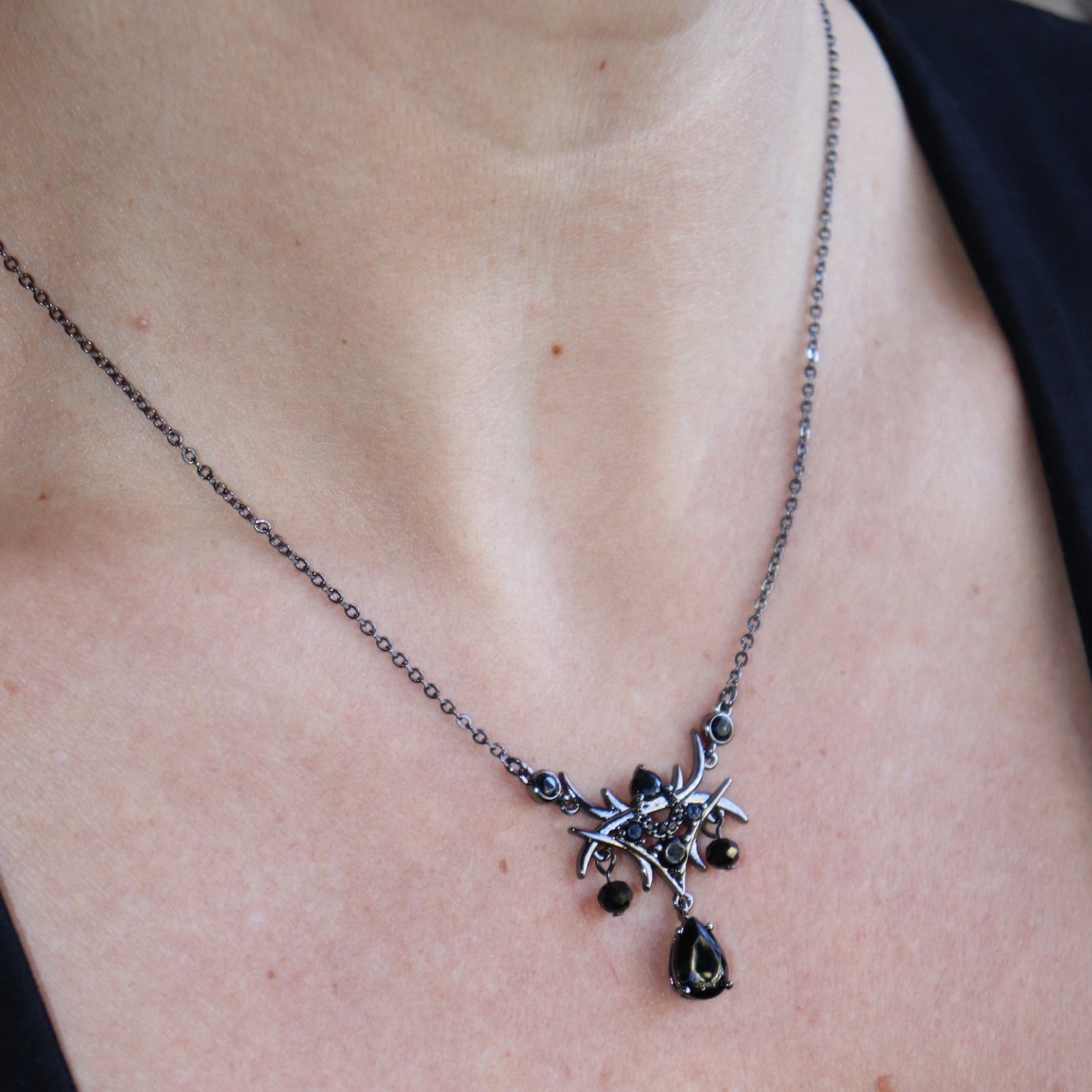 Someone wearing the Dark Fae Brass Plated Necklace with a black tank.