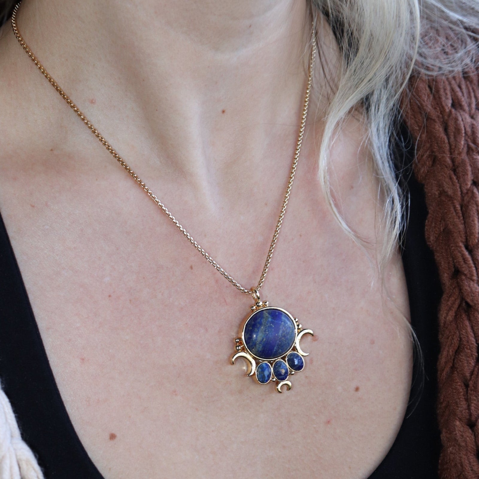 Someone wearing the lapis lazuli Priestess Gold Brass Necklace with a black tank.