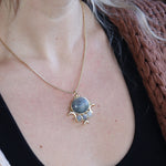 Someone wearing the labradorite Priestess Gold Brass Necklace with a black tank.