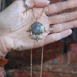 Someone holding the labradorite Priestess Gold Brass Necklace.