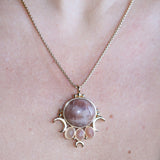 An up-close image of someone wearing the sunstone Priestess Gold Brass Necklace with a black tank.