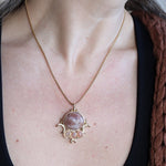 Someone wearing the sunstone Priestess Gold Brass Necklace with a black tank.