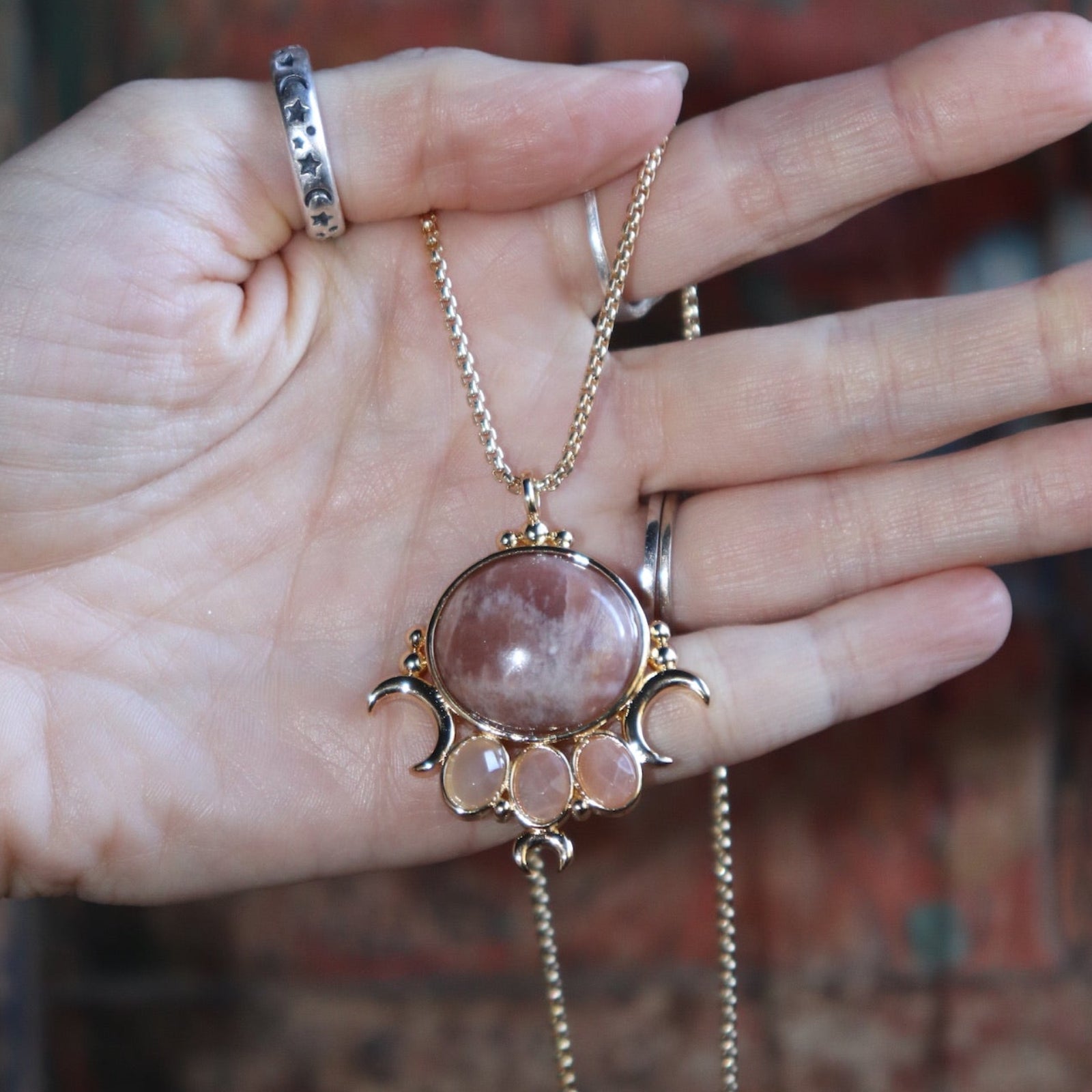 Someone holding the sunstone Priestess Gold Brass Necklace.