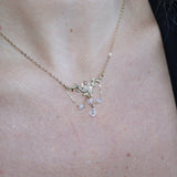 Someone wearing the Fairy Glen Gold Necklace with a black tank and a cardigan.