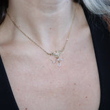 Someone wearing the Fairy Glen Gold Necklace with a black tank and a cardigan.