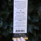 Someone holding the Samhain Premium Incense in front of greenery, showing off the back.
