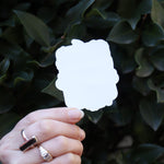 Someone holding the Vintage Halloween Sticker in front of a green bush, showing off the back.