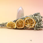 The Citrus Harvest Fall & Winter Sage Bundle in front of a crystal tower all on a pink and yellow background.