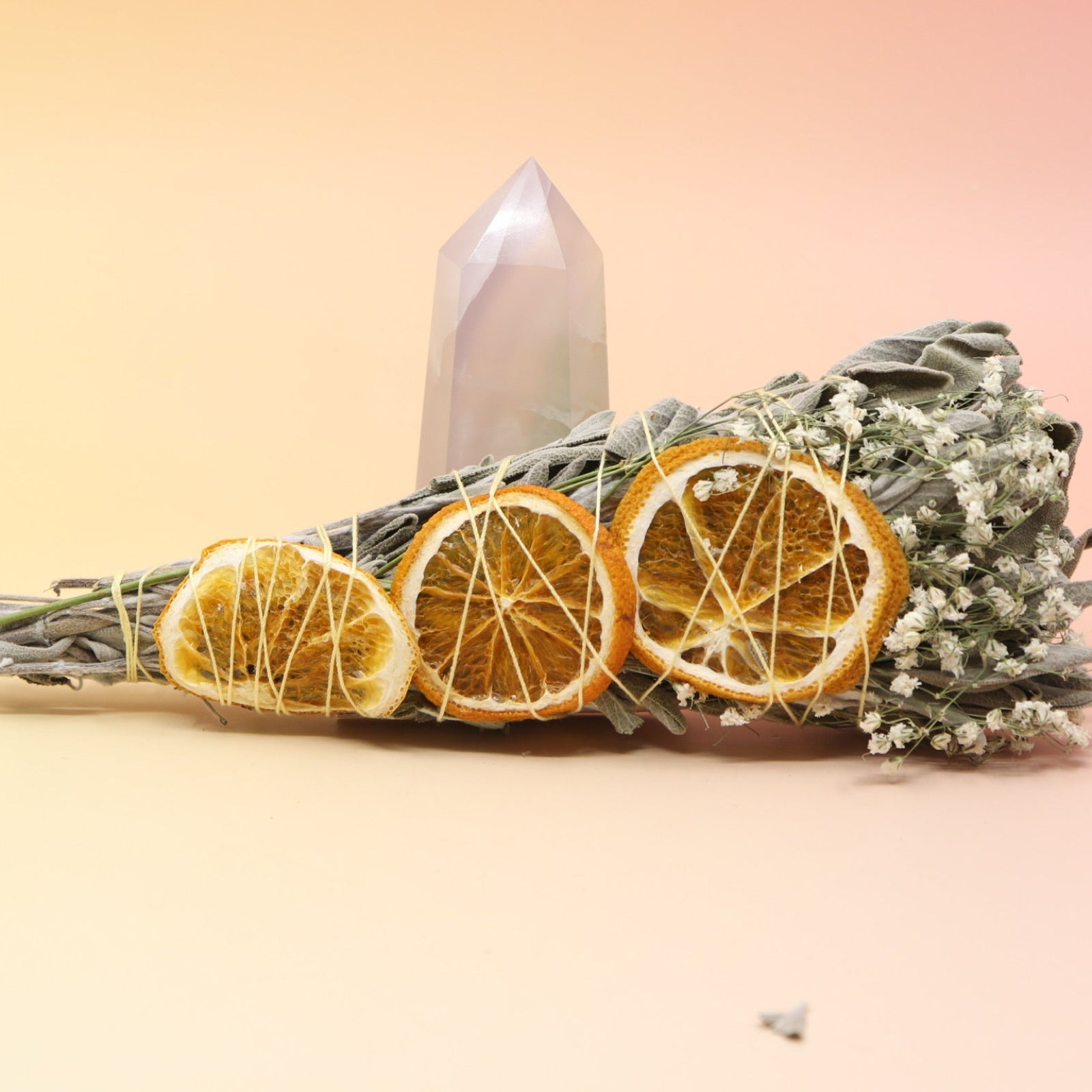 The Citrus Harvest Fall & Winter Sage Bundle in front of a crystal tower all on a pink and yellow background.